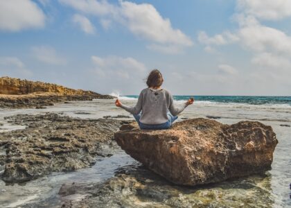 Woman meditating by the ocean on a stone